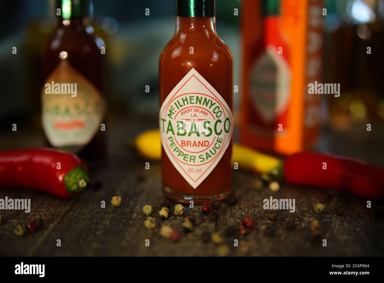 Viersen, Germany - July 9. 2020: Closeup of Tabasco hot chipotle pepper sauce on wood table with peppercorns and chillis (focus on "A" in center) Stock Photo