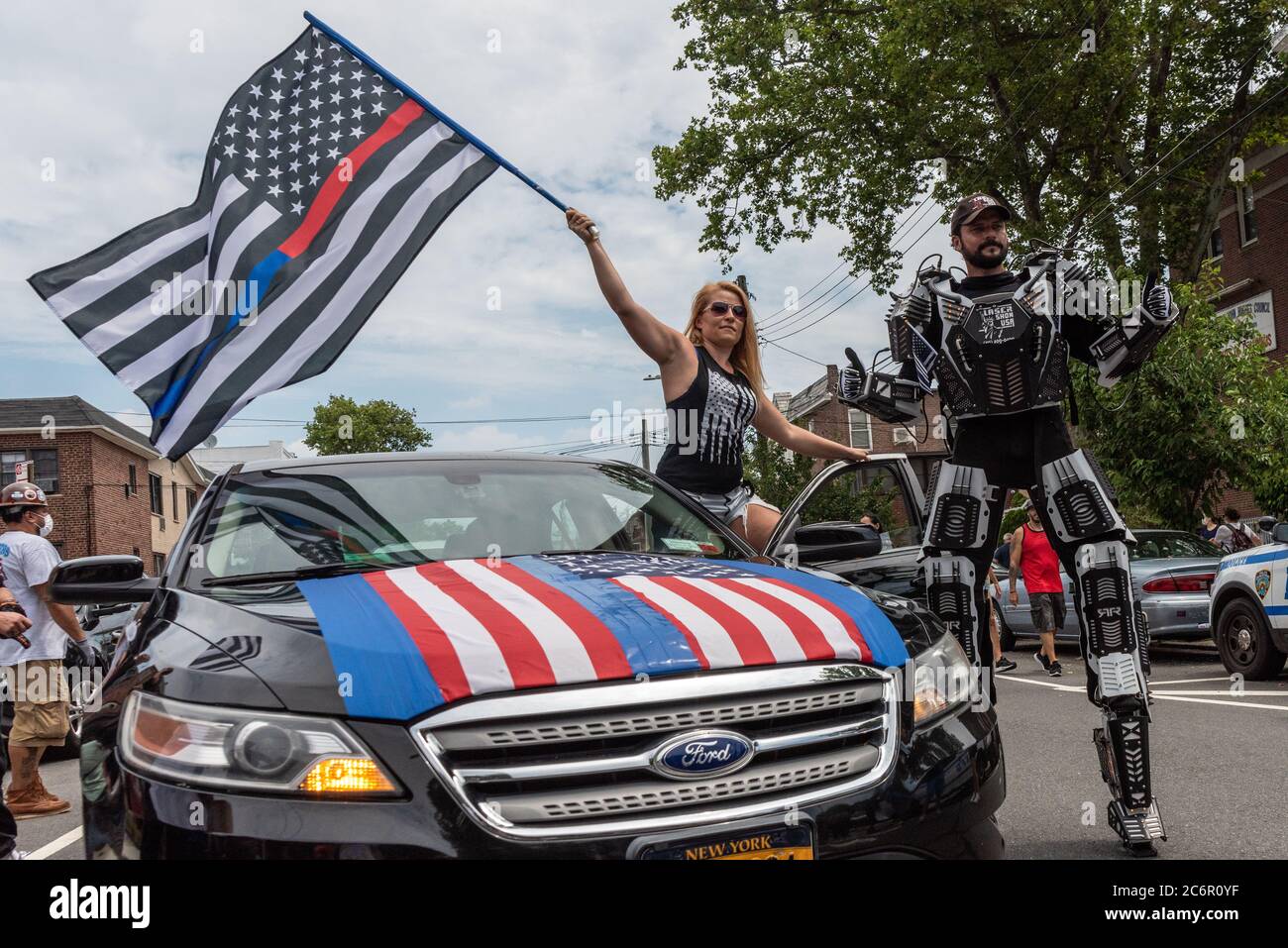 A Woman Waving A Thin Red And Thin Blue Line Flag Poses With A Guy In Robot Gear At A Blue Lives Matter Rally In Bay Ridge Brooklyn On July 11 2020