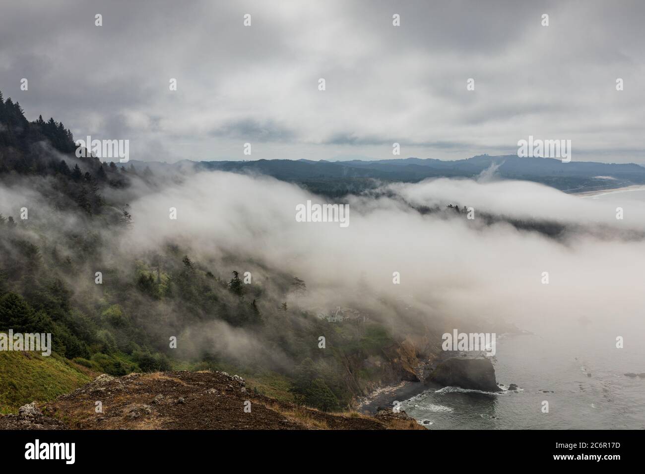 Fog rolling in from the sea over tree covered coastal hills in Oregon Stock Photo