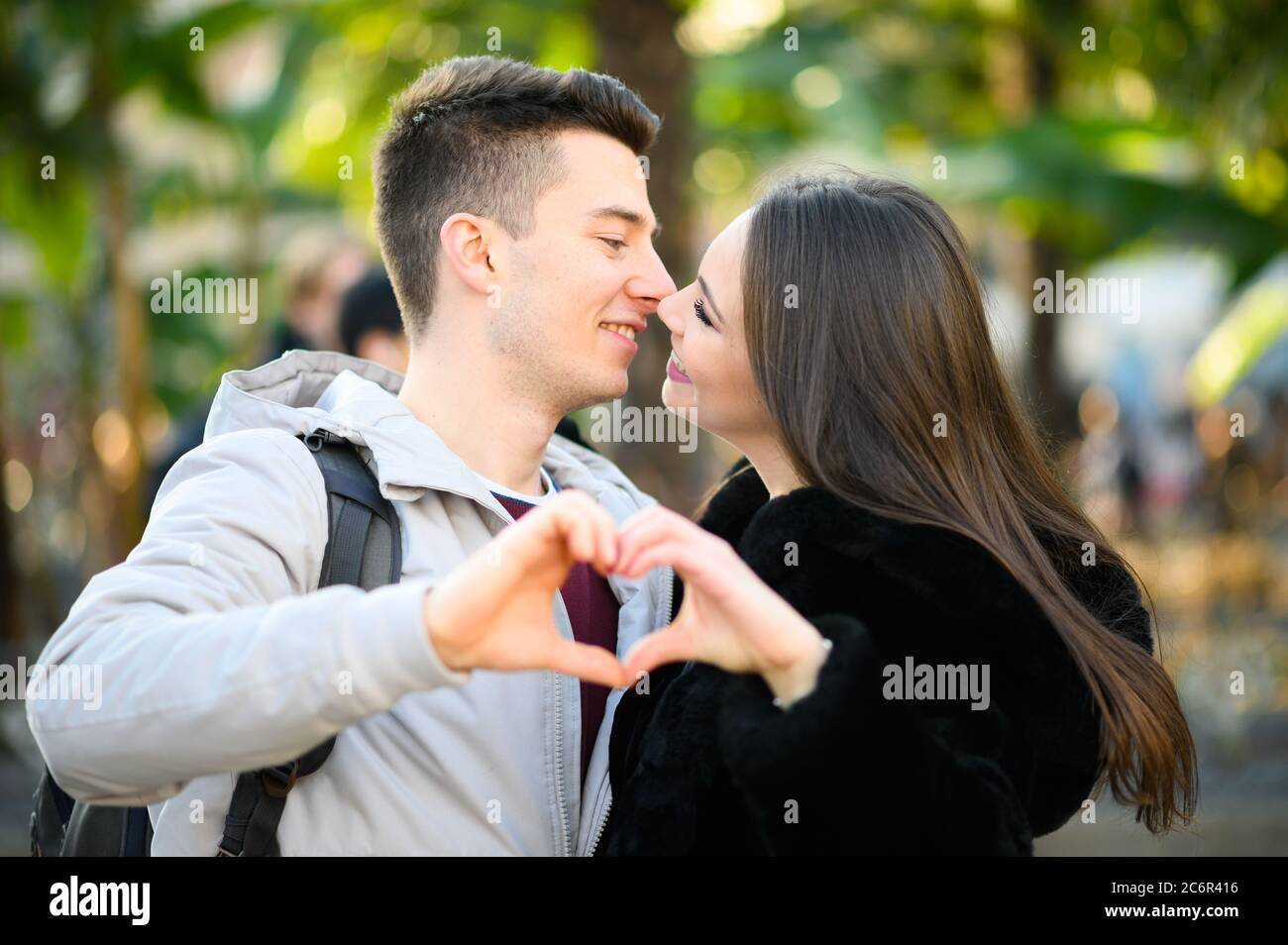 Young couple kissing while making a heart shape with their hands Stock
