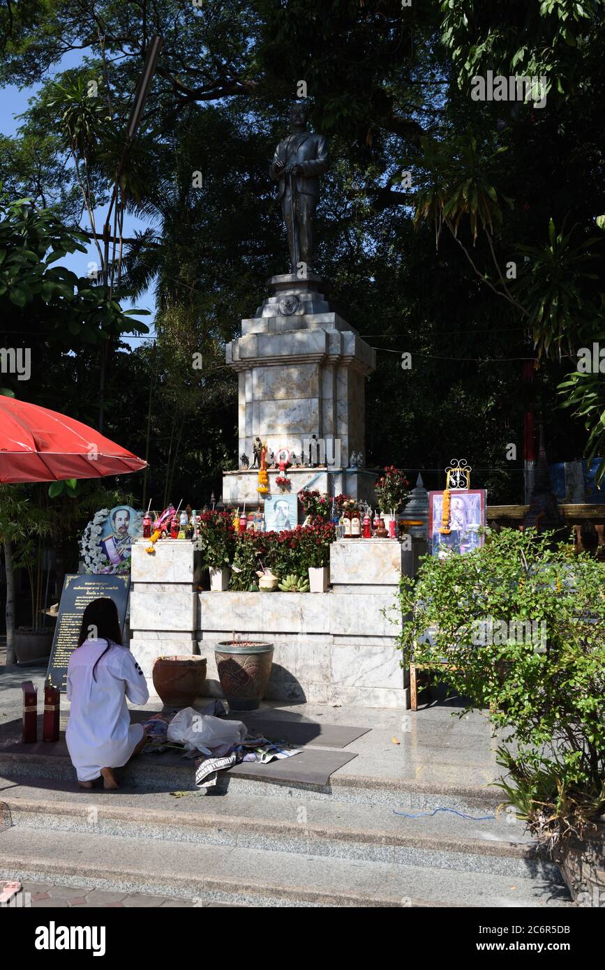 Woman giving offerings at the statue of King Chulalongkorn, also known as Rama V, in the grounds of Wat Chai Mongkhon, Chiang Mai, Thailand Stock Photo