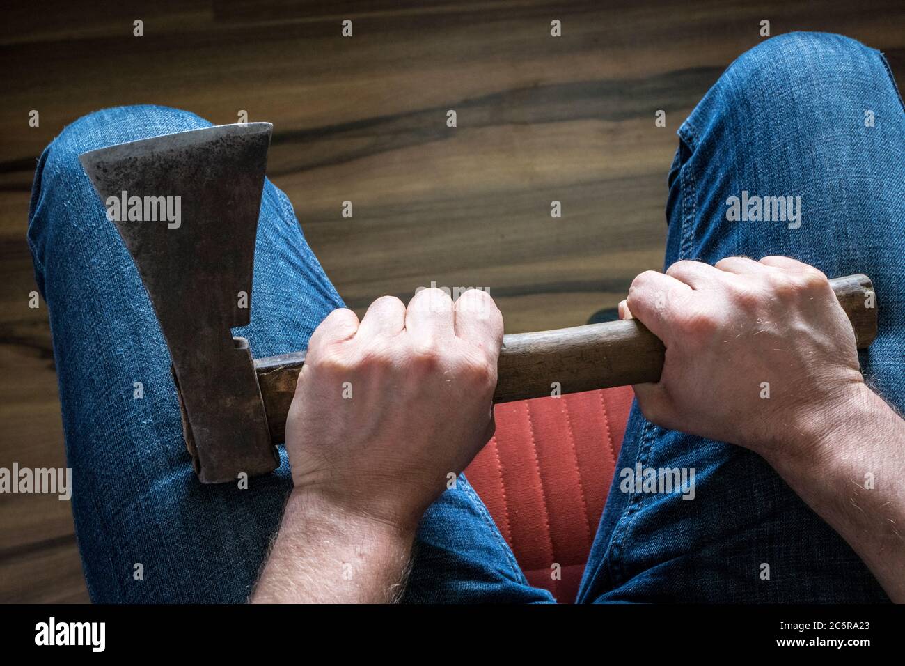 A man squeezing an ax in his knees. The concept, Domestic violence, social problems, crime Stock Photo
