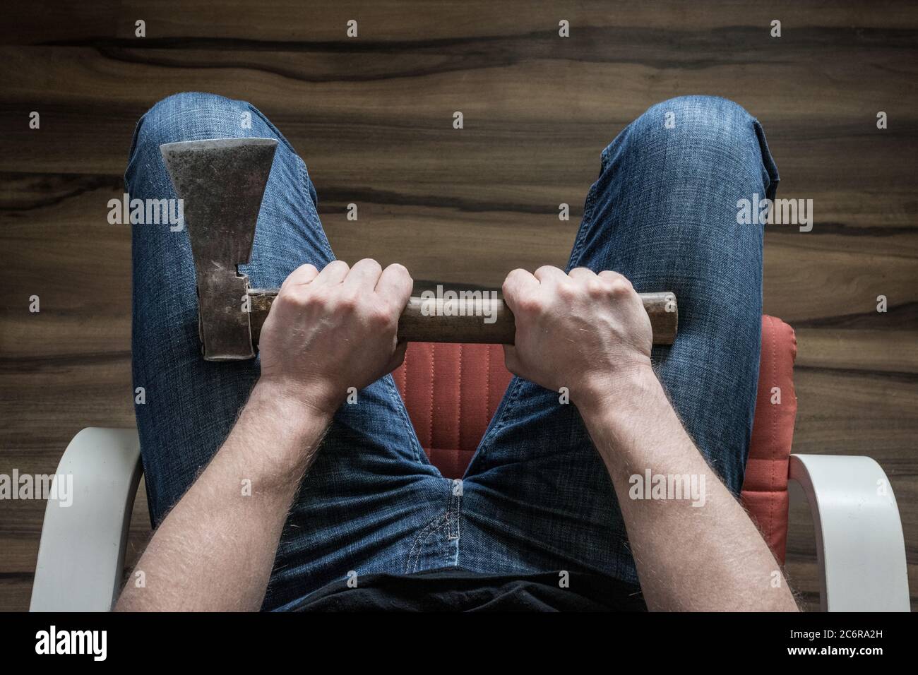 A man squeezing an ax in his knees. The concept, Domestic violence, social problems, crime Stock Photo