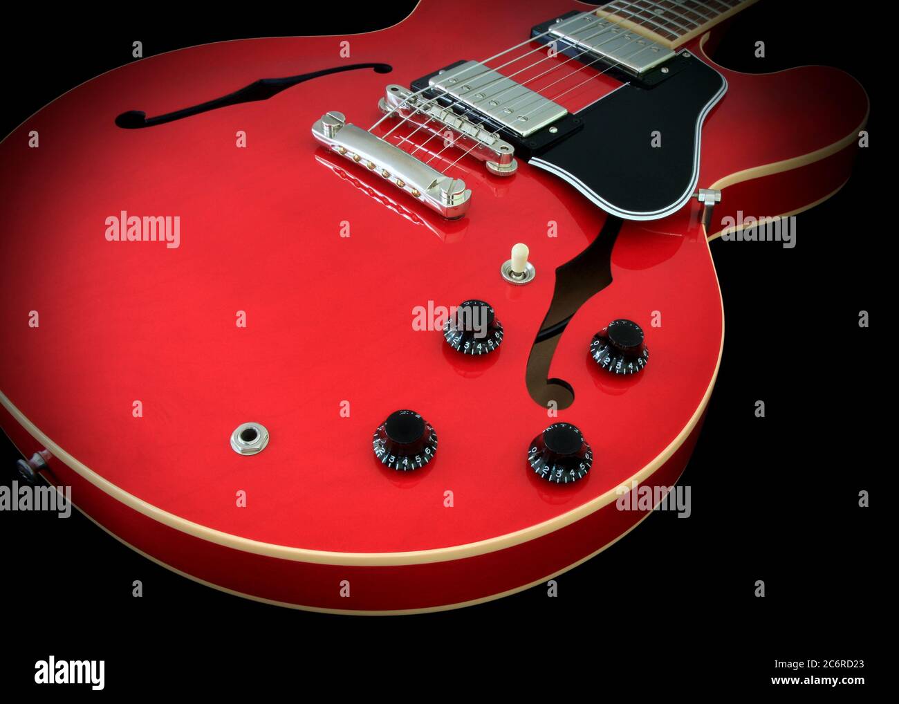 Detail of a Gibson ES-335 semi-hollow electric guitar showing the soundholes, humbucker pickups, bridge, volume and tone knobs, selector switch, pickguard, cherry finish, and binding. Stock Photo