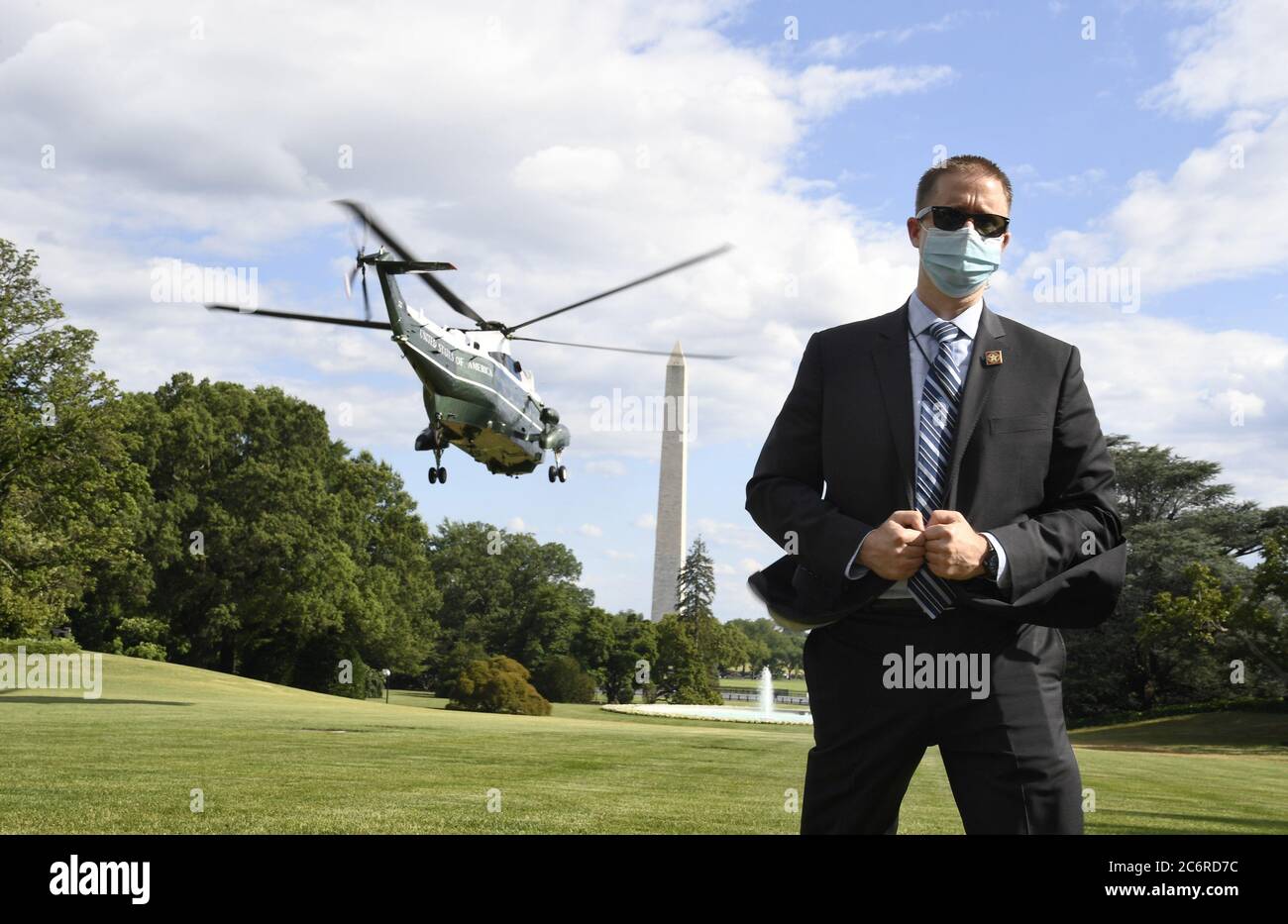 Washington, United States. 11th July, 2020. A US Secret Service agent, wearing a mask to protect against COVID-19, stands on the South Lawn as Marine One lifts off with President Donald Trump, departing the White House in Washington, DC on Saturday, July 11, 2020 for a visit to Walter Reed National Military Medical Center, in Bethesda Maryland. Photo by Mike Theiler/UPI Credit: UPI/Alamy Live News Stock Photo