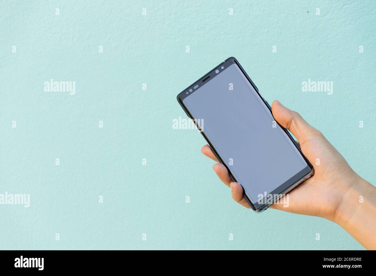 BANGKOK, THAILAND : Dec 30, 2017 - Woman hold smart phone Samsung galaxy note 8 (Android OS) on blue concrete background Stock Photo
