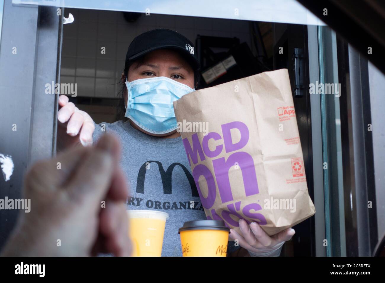 McDonald's cashier wearing mask to protect from the coronavirus handing food to customer through drive-up car window. St Paul Minnesota MN USA Stock Photo