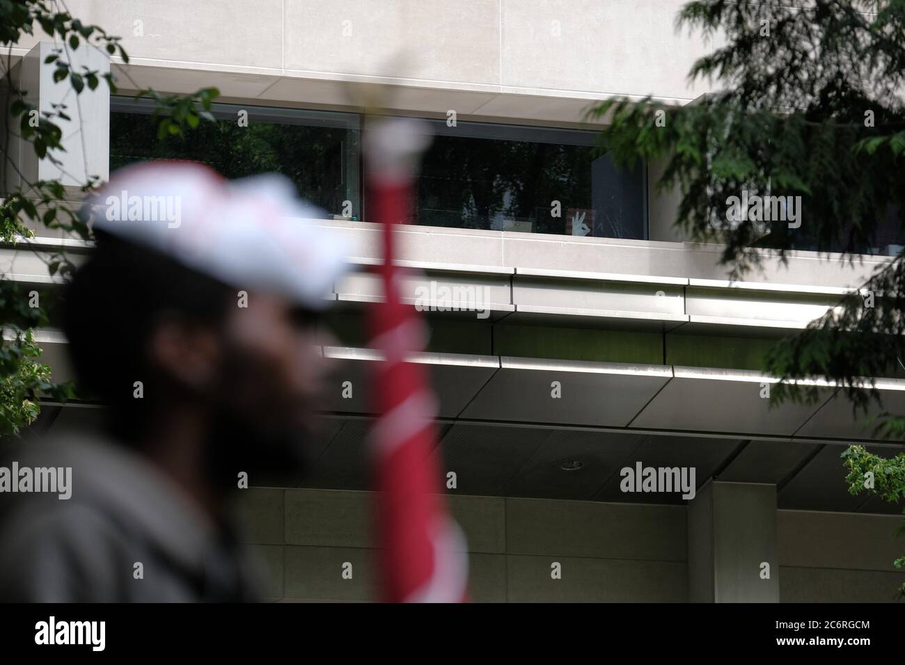 Portland, USA. 11th July, 2020. A protester stands in front of an 'okay' gesture on repeated rows of the number 3, outwardly displayed from the Mark O. Hatfield federal courthouse in Portland, Ore., on July 11, 2020. Last year the Anti-Defamation listed the gesture as a symbol of hate as a result of it's use by white supremacists who falsely promoted it to represent 'wp' or 'white power' on the website 4chan beginning in 2017. (Photo by Alex Milan Tracy/Sipa USA) Credit: Sipa USA/Alamy Live News Stock Photo