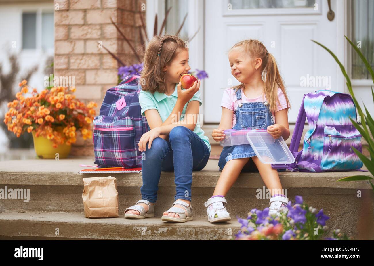 Pupils of primary school with lunch-boxes in hands. Girls with ...