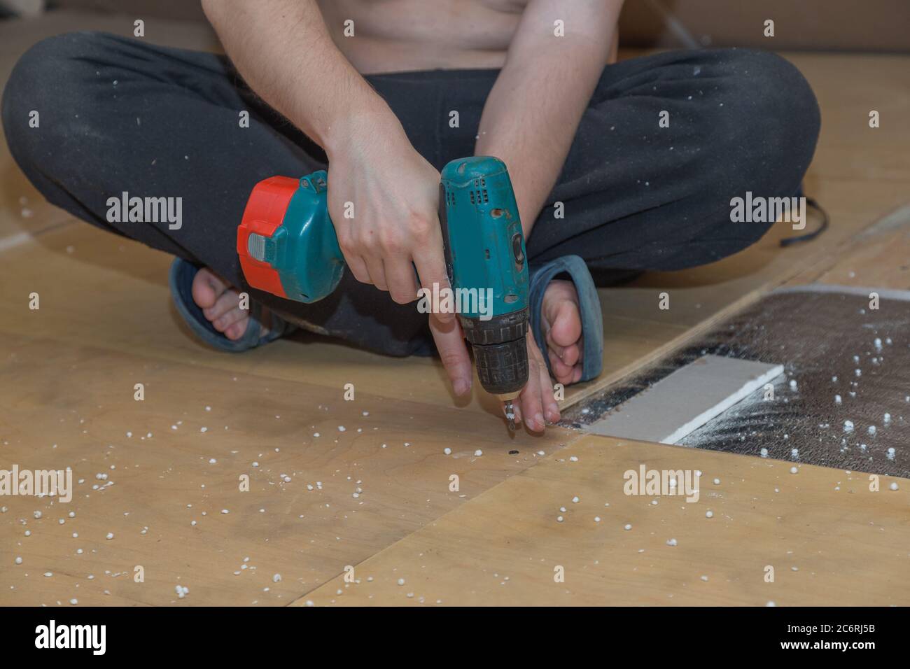 the hand holds a screwdriver and screws the screw into a plywood sheet Stock Photo Alamy
