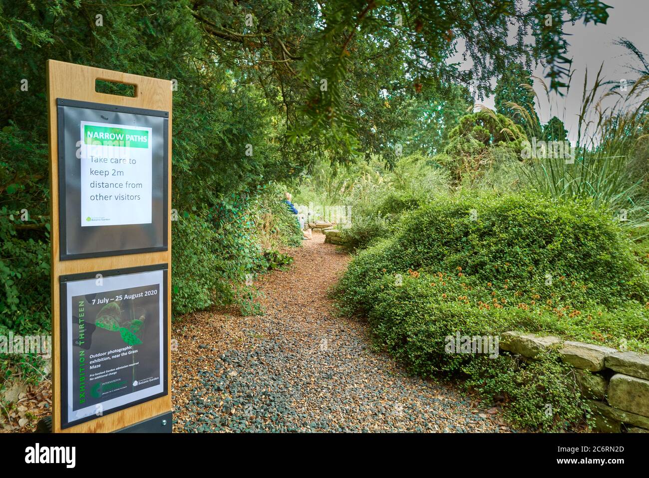 Social distancing precautions (2m apart) on a narrow path at the university of Cambridge botanic garden, July 2020, due to the coronavirus epidemic. Stock Photo