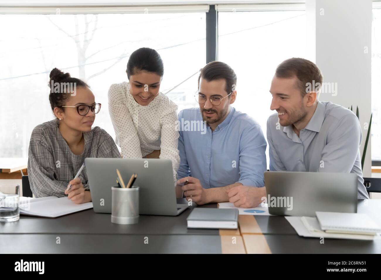 Smiling multiracial employees work on laptop in office Stock Photo
