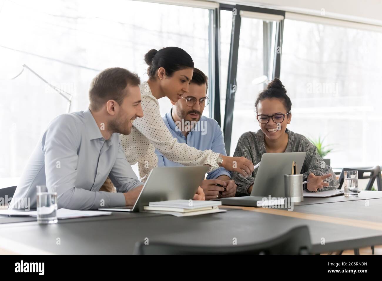 Smiling diverse colleagues cooperate using laptop together Stock Photo