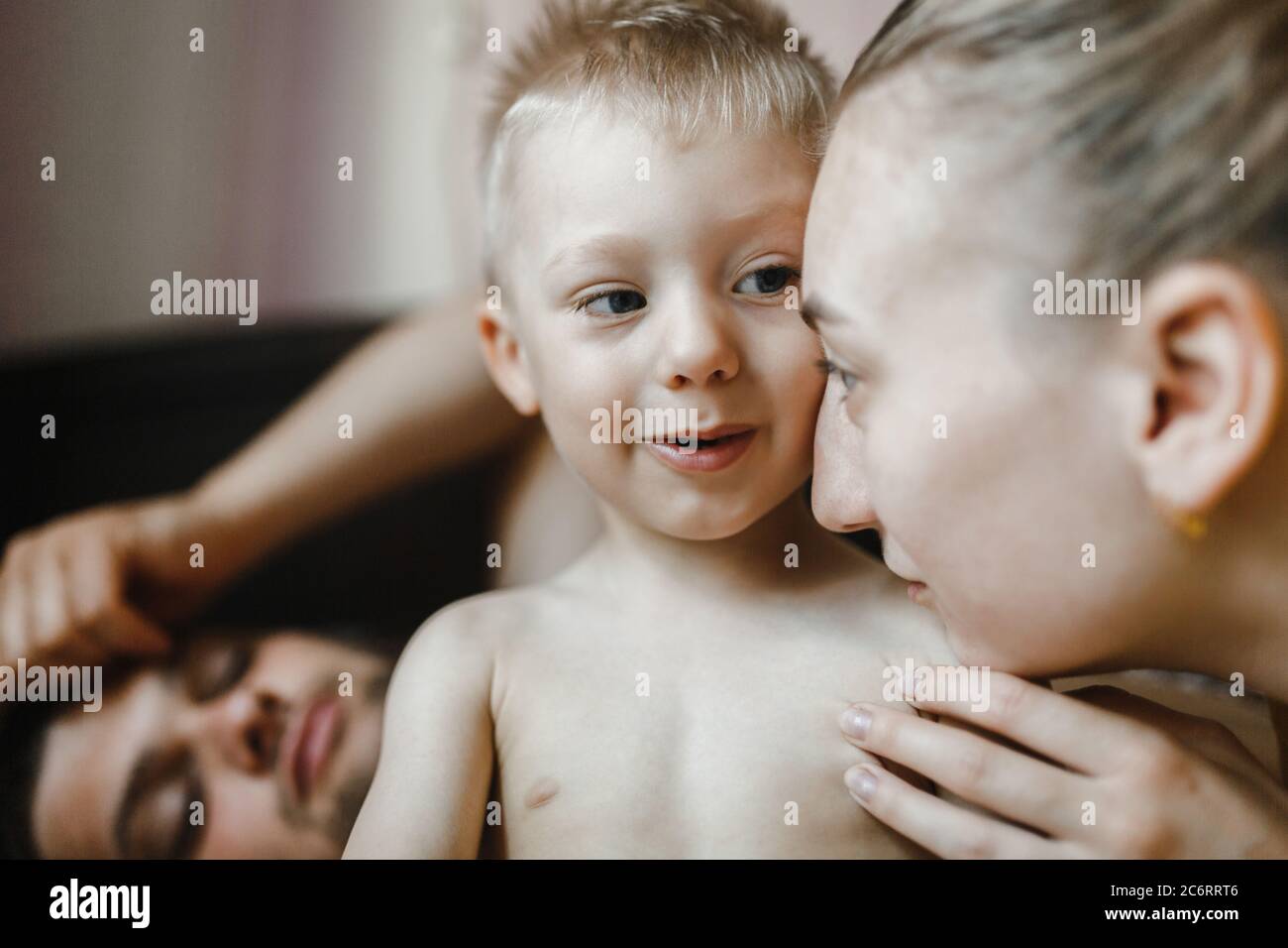 Mother speaking to little son while father is looking at them in the room. Family portrait. Happy family Stock Photo