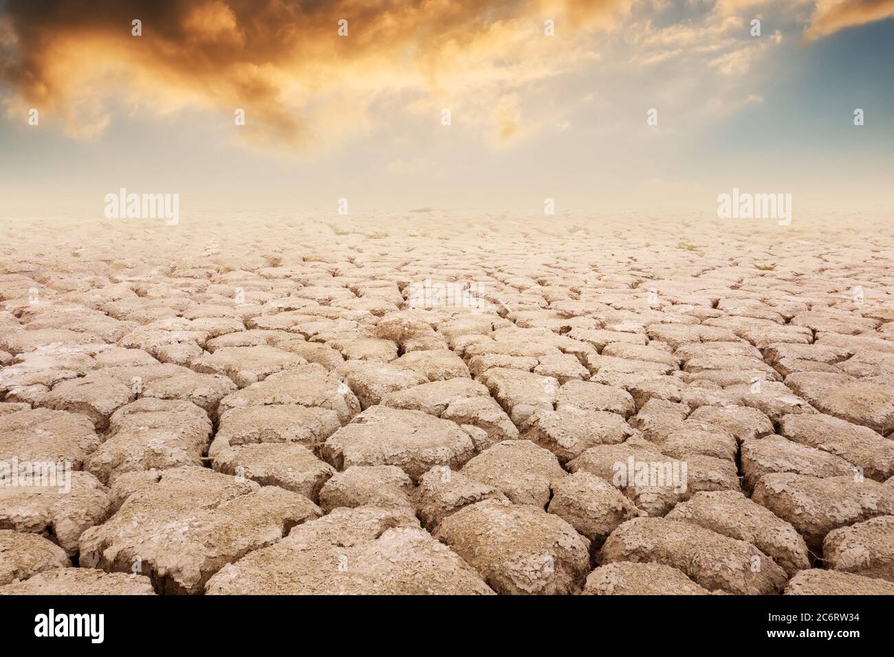 A view of a dry land, with orange clouds and sunset backgraund. Summer season drought farmlands. Global warming and climate change concept Stock Photo