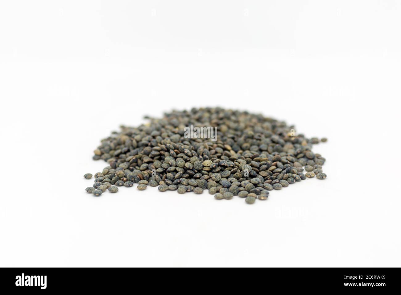 A heap of dried puy lentils against a white background, with a shallow depth of field Stock Photo