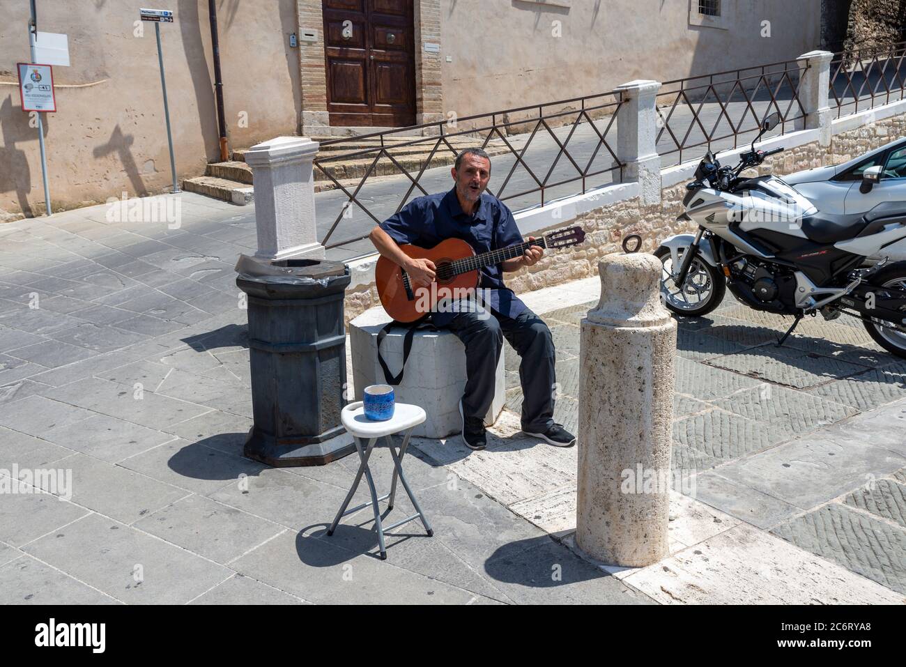 assisi,italy july 11 2020:a street artist with a guitar in the sun Stock Photo