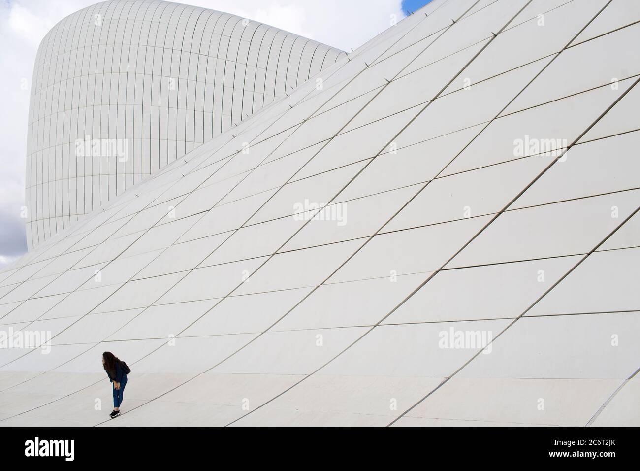 Two teenage girls running up the front of the Heydar Aliyev center, designed by Zaha Hadid the centerpiece of modern architecture in Baku Azerbaijan Stock Photo