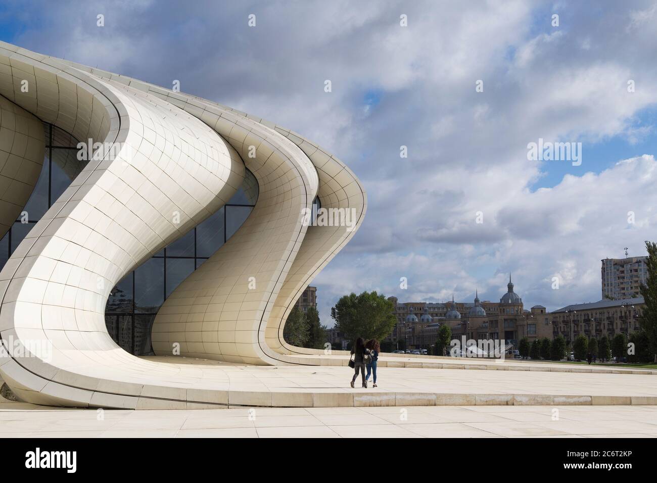 Two teenage girls running up the front of the Heydar Aliyev center, designed by Zaha Hadid the centerpiece of modern architecture in Baku Azerbaijan Stock Photo