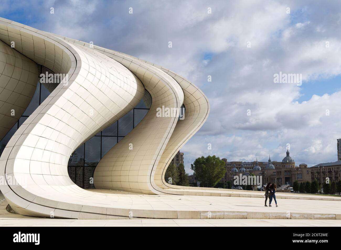 Two teenage girls running up the front of the Heydar Aliyev center, designed by Zaha Hadid the centerpiece of modern architecture in Baku Azerbaijan Stock Photo