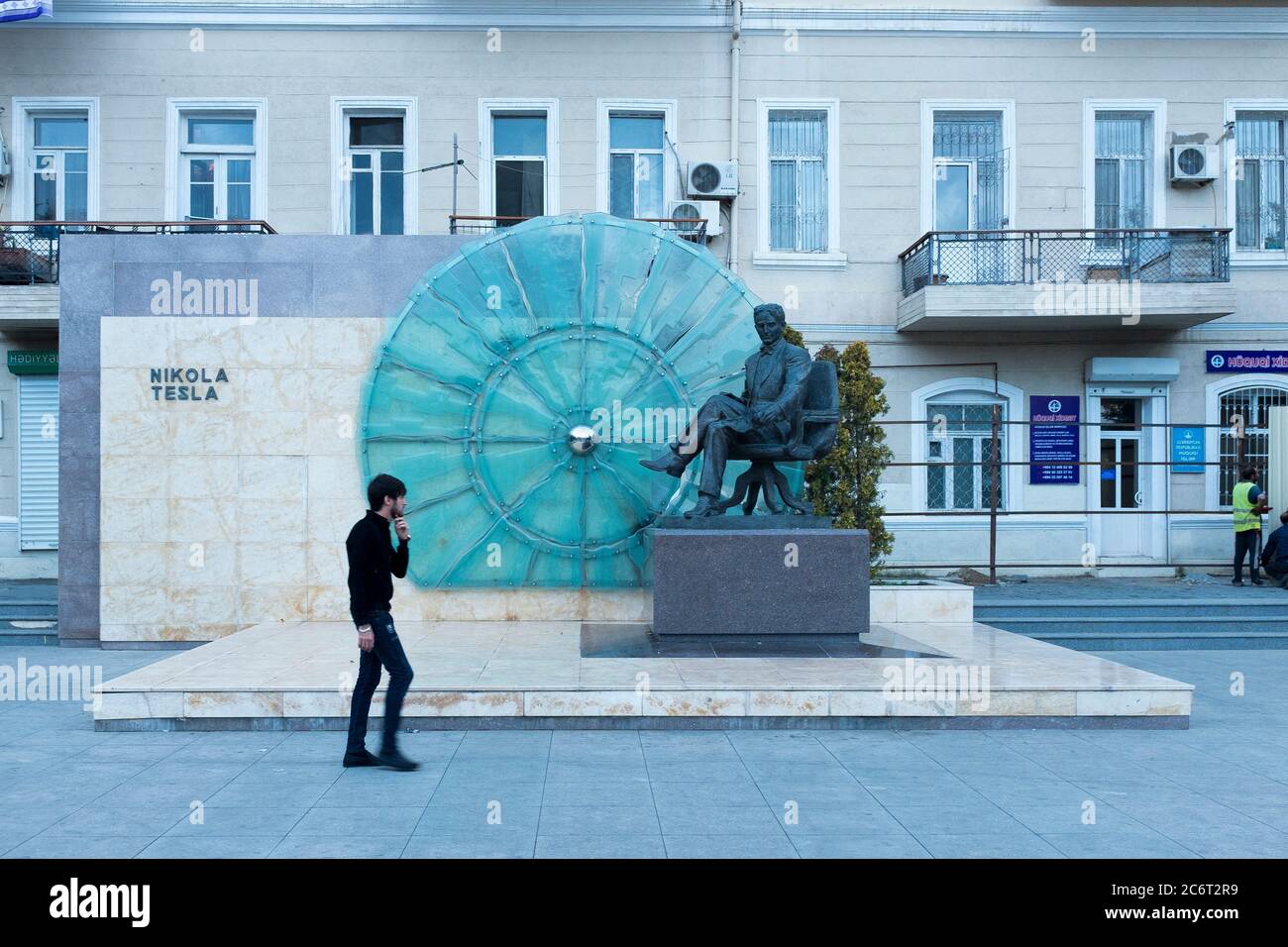 A man walks past a statue and memorial to scientist and inventor Nikolas Tesla in Baku the capital city of Azerbaijan Stock Photo