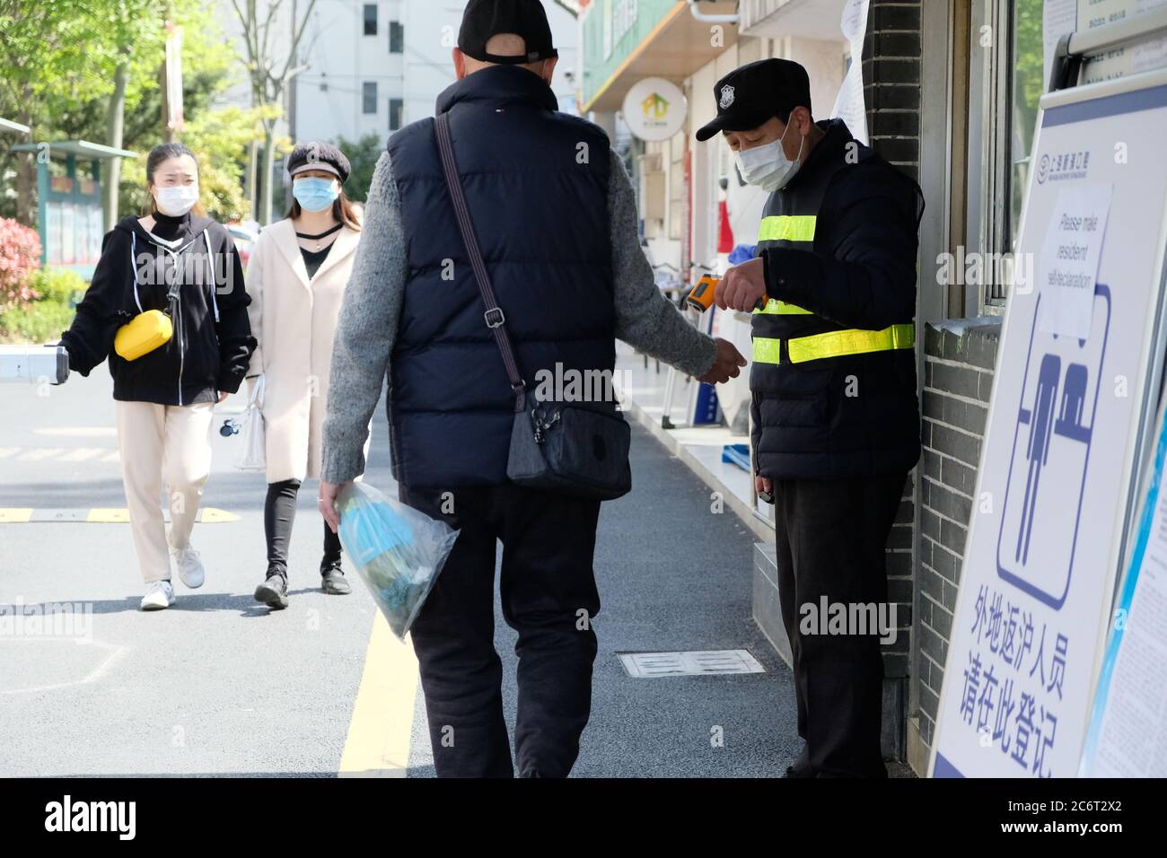 To prevent and control coronavirus, community worker taking temperature of resident at entrance. Stock Photo