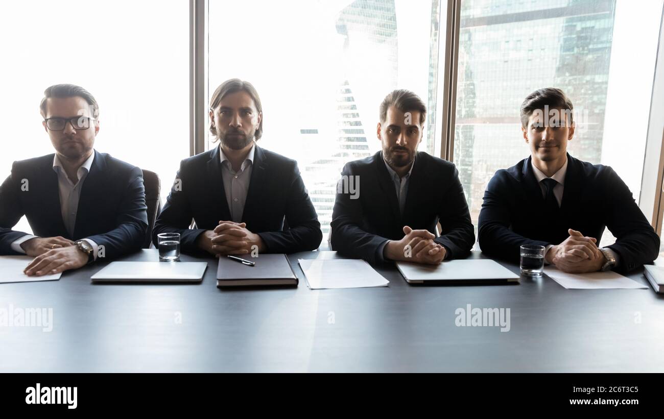 Group of focused male professional headhunters recruiters sitting at table. Stock Photo