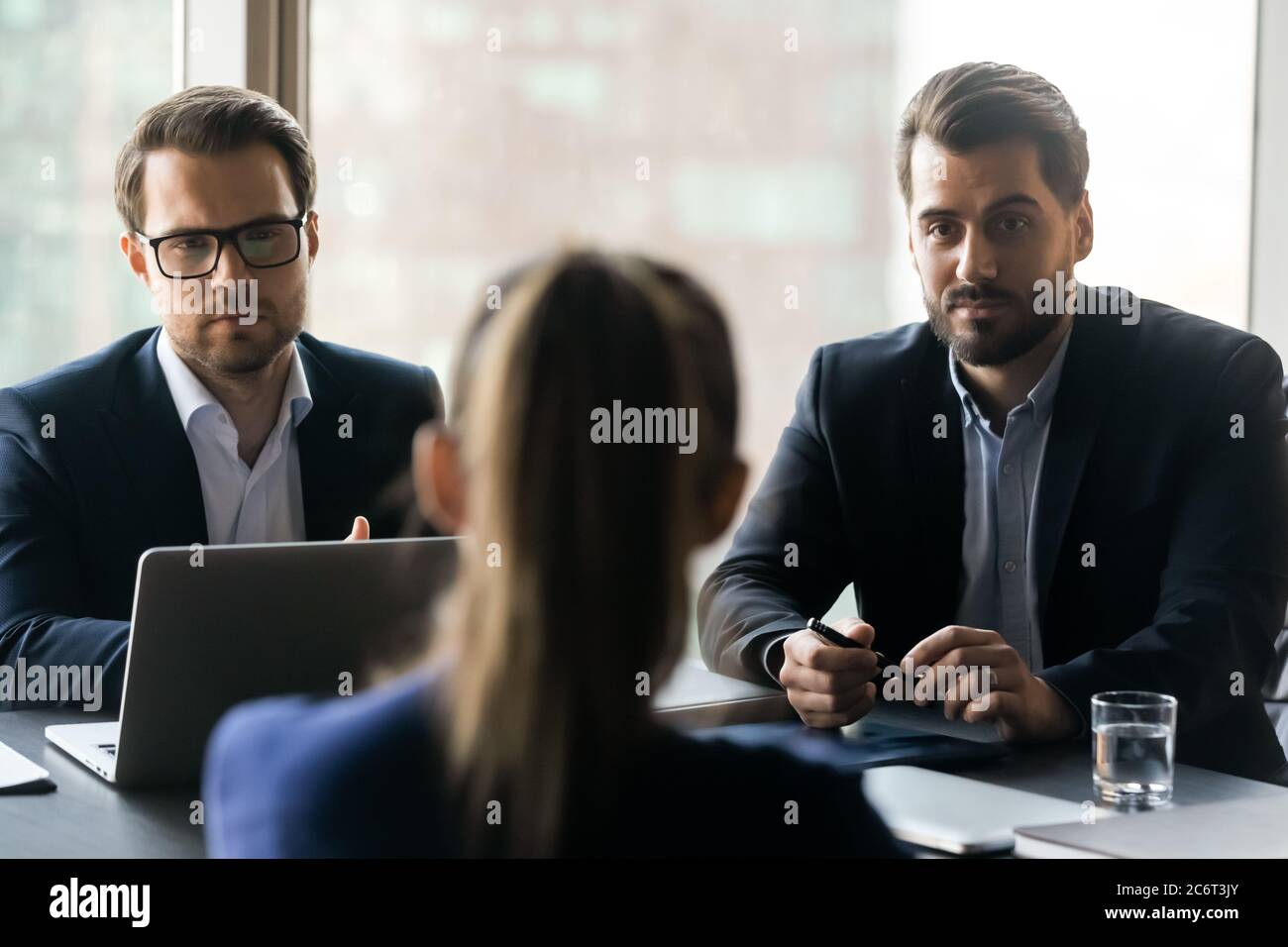 Serious male employers listening to female job seeker at interview. Stock Photo