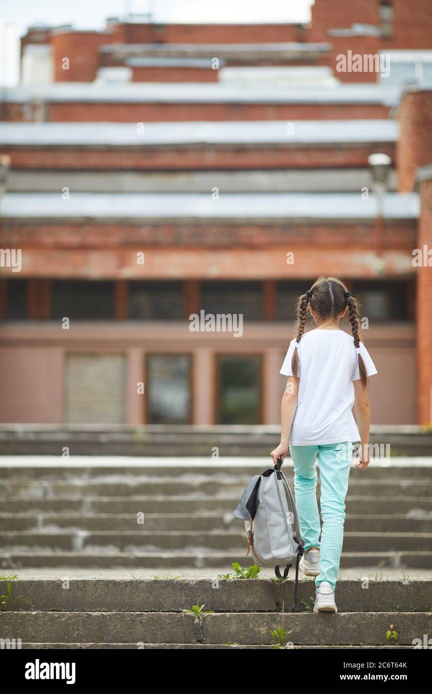 Full length portrait of teenage schoolgirl crying while sitting on stairs outdoors with smiling friend comforting her, copy space Stock Photo