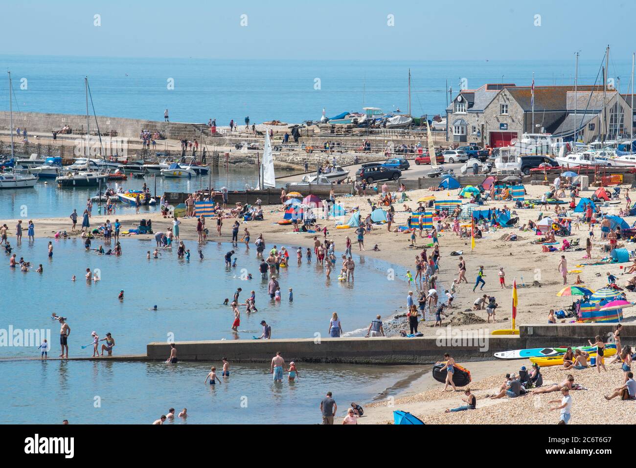 Lyme Regis, Dorset, UK. 12th July, 2020. UK Weather: Crowds of beachgoers flock to the picturesque seaside resort of Lyme Regis to soak up the scorching hot sunshine. Families, visitors and sunseekers packed out the beach this weekend to enjoy the best of the sunny weather as tourists make a wlecome return to the popular resort. Credit: Celia McMahon/Alamy Live News Stock Photo