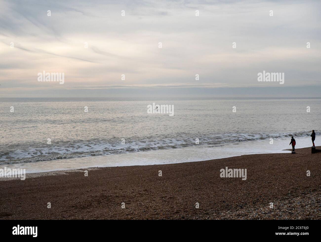 Two People Watching A Paddleboarder In The Early Evening Light Off The Coast At Brighton East Sussex Uk Stock Photo Alamy