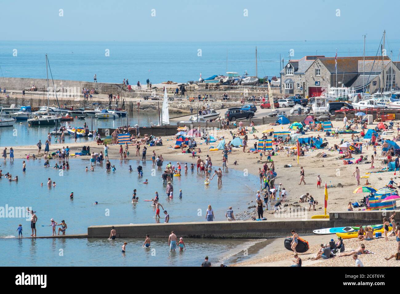 Lyme Regis, Dorset, UK. 12th July, 2020. UK Weather: Crowds of beachgoers flock to the picturesque seaside resort of Lyme Regis to soak up the scorching hot sunshine. Families, visitors and sunseekers packed out the beach this weekend to enjoy the best of the sunny weather as tourists make a wlecome return to the popular resort. Credit: Celia McMahon/Alamy Live News Stock Photo