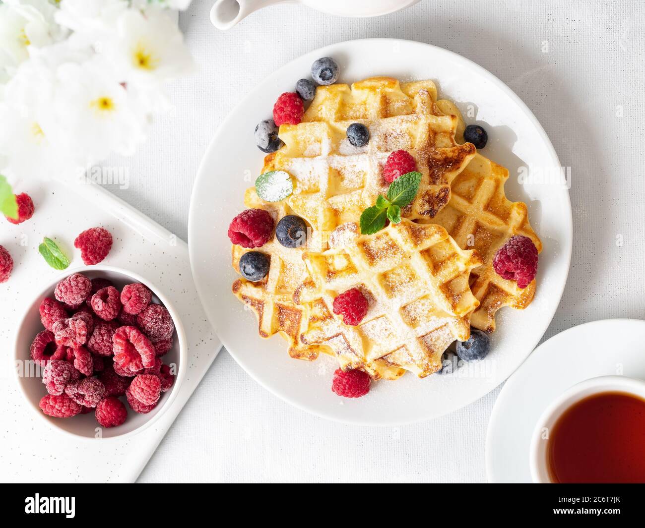 Belgian waffles with raspberries, blueberries, curd and tea, top view