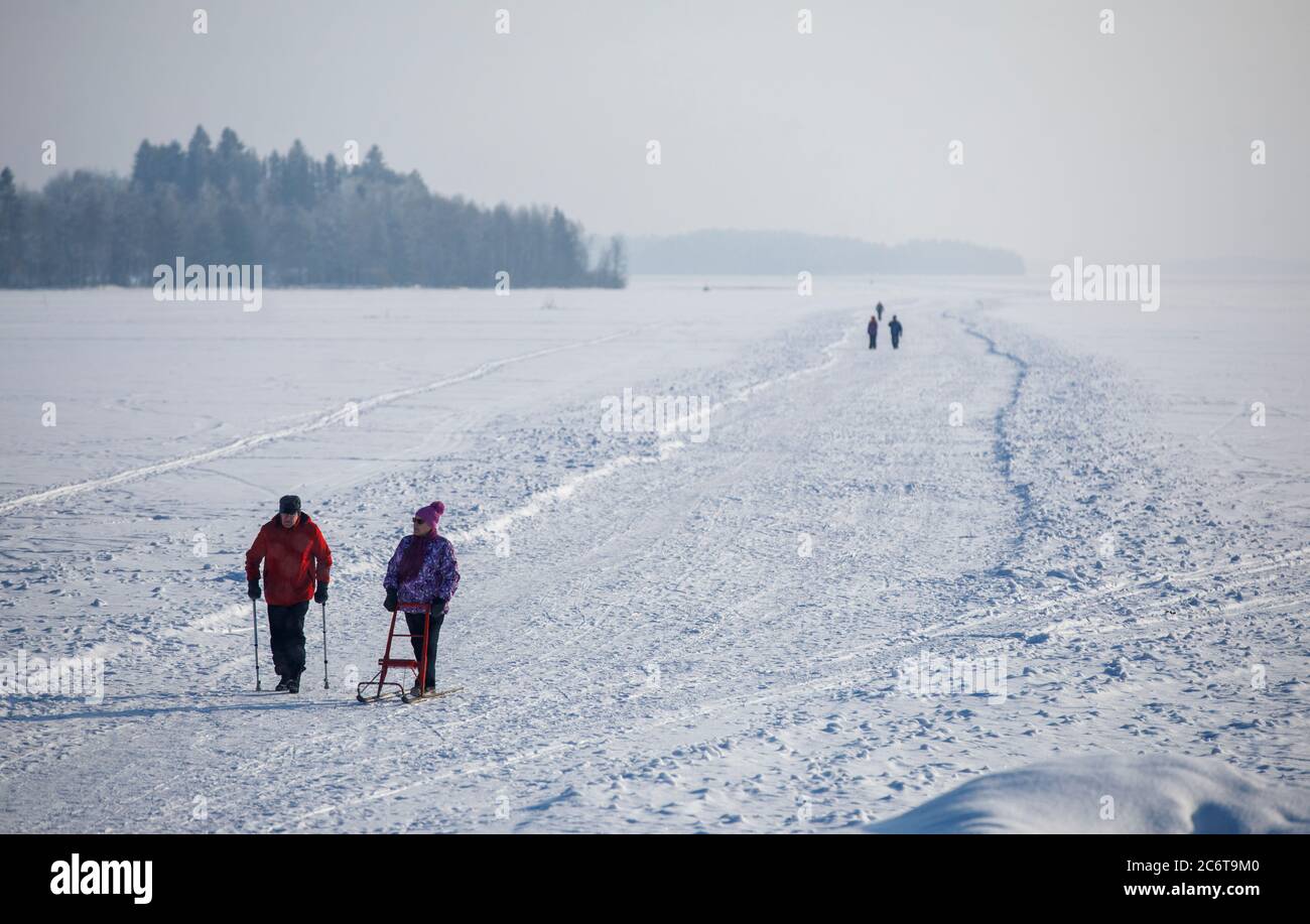 People walking on an ice road , plowed to the lake ice at Winter . Man with  crutches and a woman with kick sled exercising , Finland Stock Photo - Alamy
