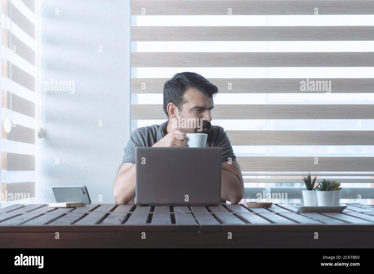 Turkish man working from home with laptop at early morning. Modern illuminated reverse light photo. Stock Photo