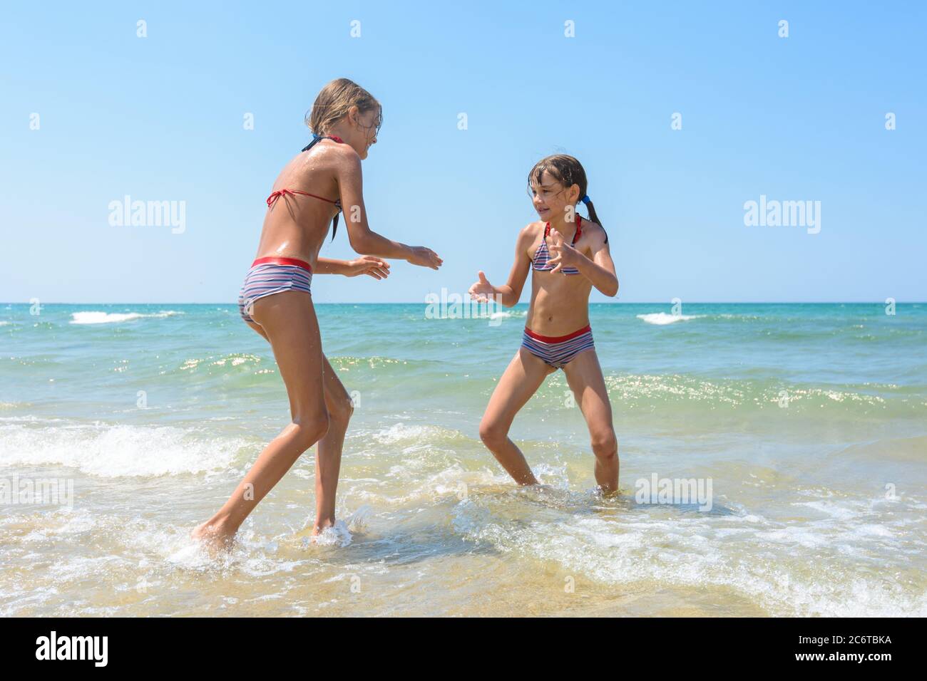 Two girls playing fight on the seashore in the water Stock Photo - Alamy