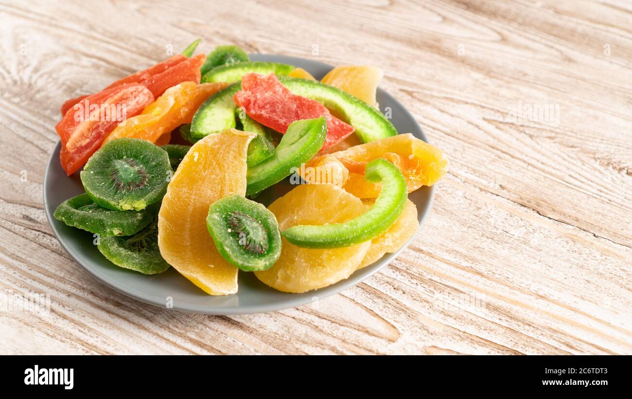 plate of dried fruits on a wooden table. kiwi, mango, papaya, melon, pineapple. do not affects blood sugar levels Stock Photo