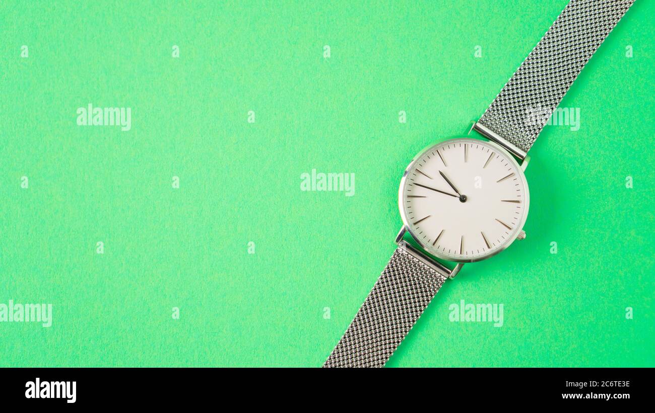 gray wristwatch on a green background. isolated woman watch. time is running away concept. watch advertisement Stock Photo