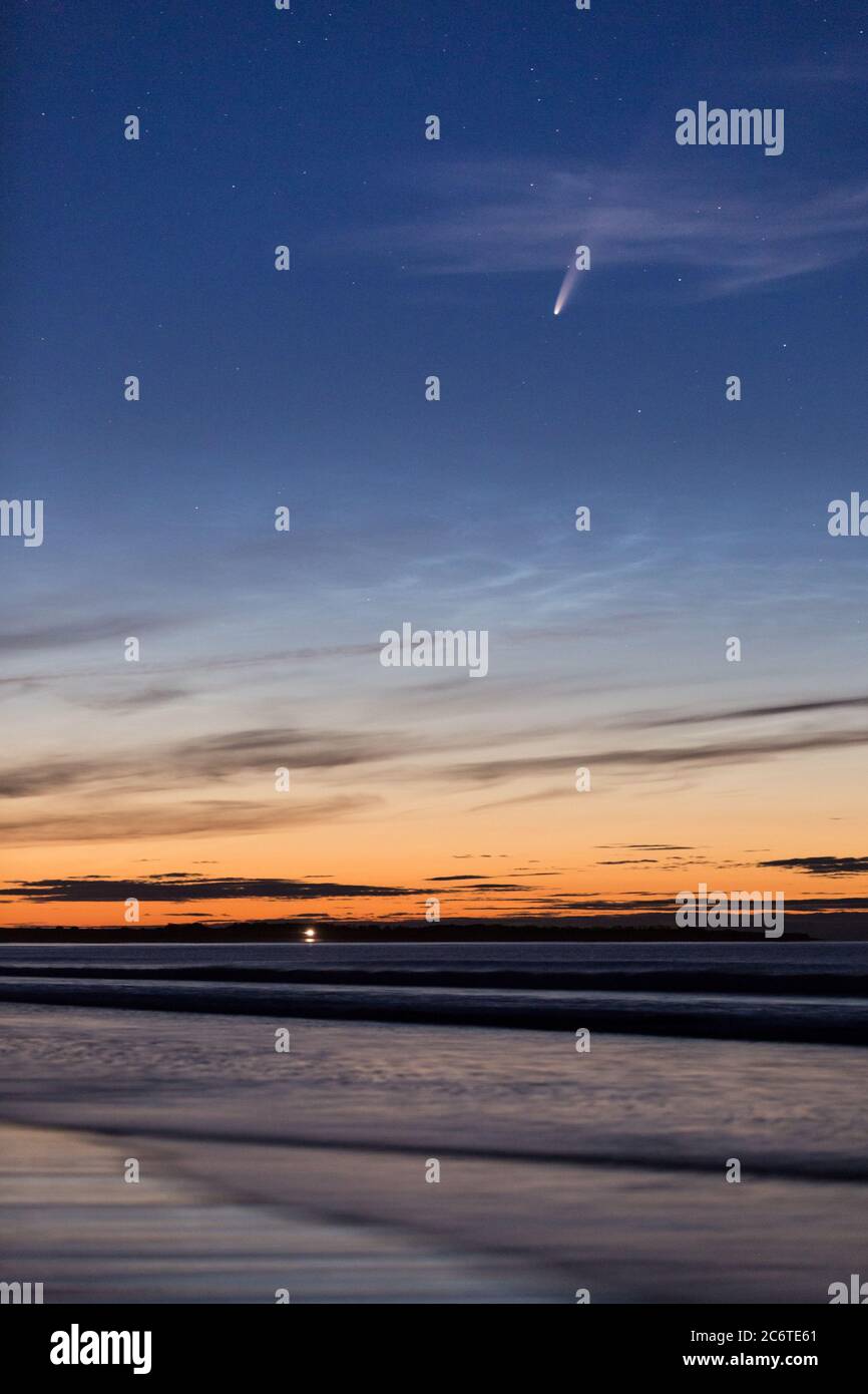 Comet NOEWISE and noctilucent cloud on the beach at Druridge Bay on the Northumberland coast, North East England in July. Stock Photo