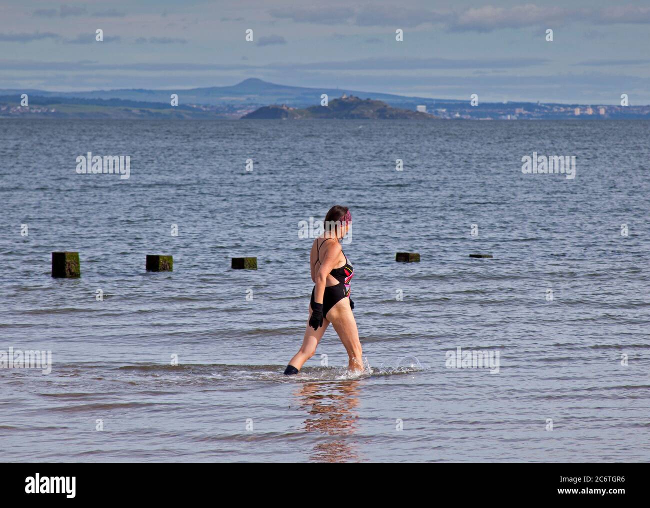 Portobello, Edinburgh, Scotland, UK 12 July 2020.Temperature 13 degrees in the morning rising to 18 degrees in afternoon with very little breeze. Over the last three months of the Coronavirus pandemic  people of all ages have healthier pursuits in their leisure time as well as the regular wild swimmer pictured taking a regular dip in the Firth of Forth. Stock Photo