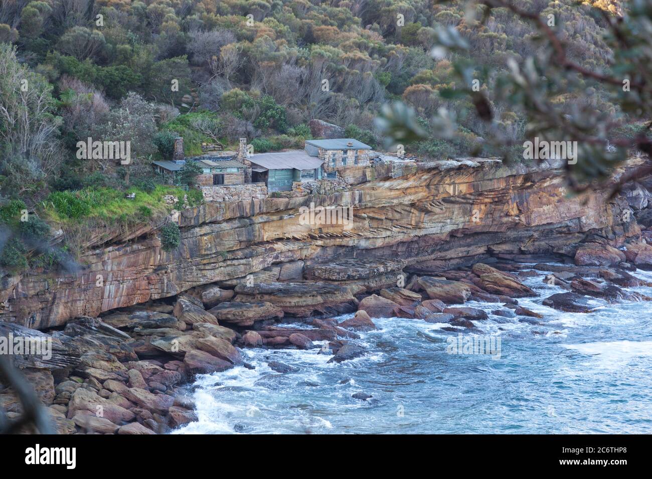 Historic old clifftop huts  at an isolated cove in National Park bushland of Sydney, Australia Stock Photo