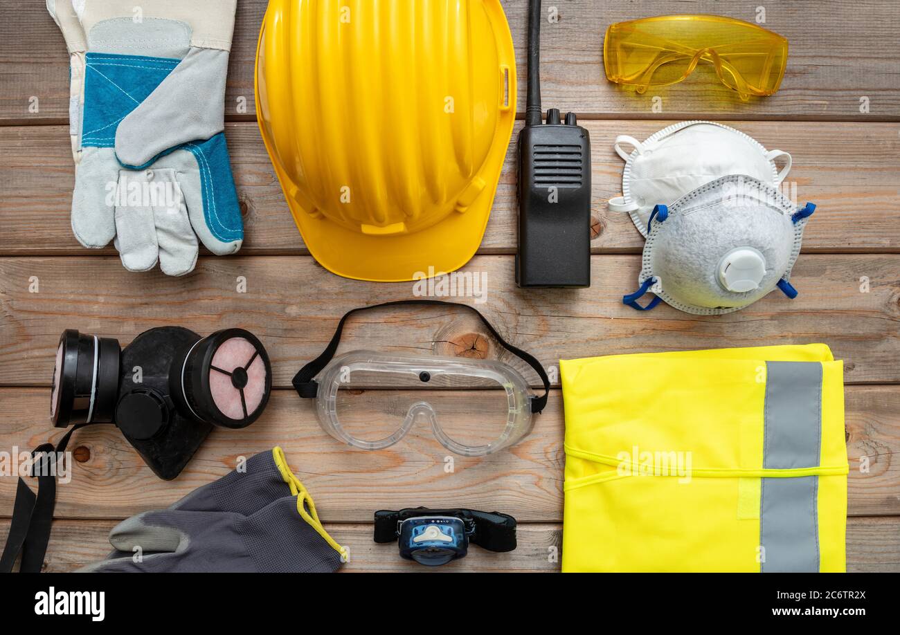 Work safety protection equipment flat lay. Industrial protective gear on wooden background. Construction site health and safety concept. Stock Photo