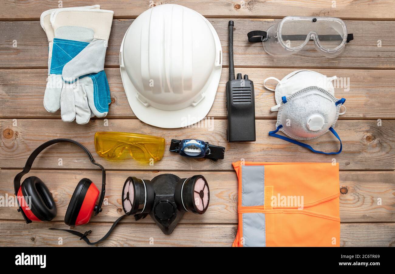 Work safety protection equipment flat lay. Industrial protective gear on wooden background. Construction site health and safety concept. Stock Photo