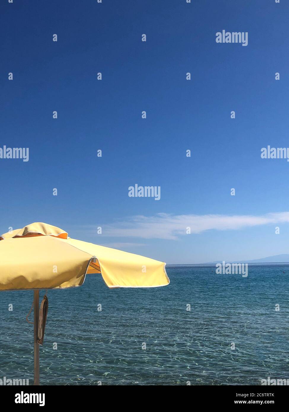 A Yellow Sun Umbrella with Sky by the Sea on Chalkidiki, Greece Stock Photo