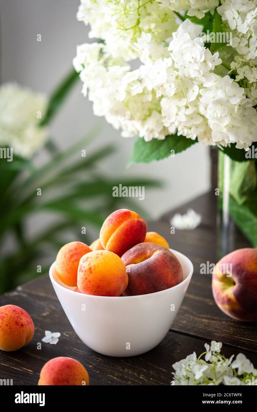 Vase of flowers viburnum opulus Roseum and ripe juicy apricots and peaches Stock Photo