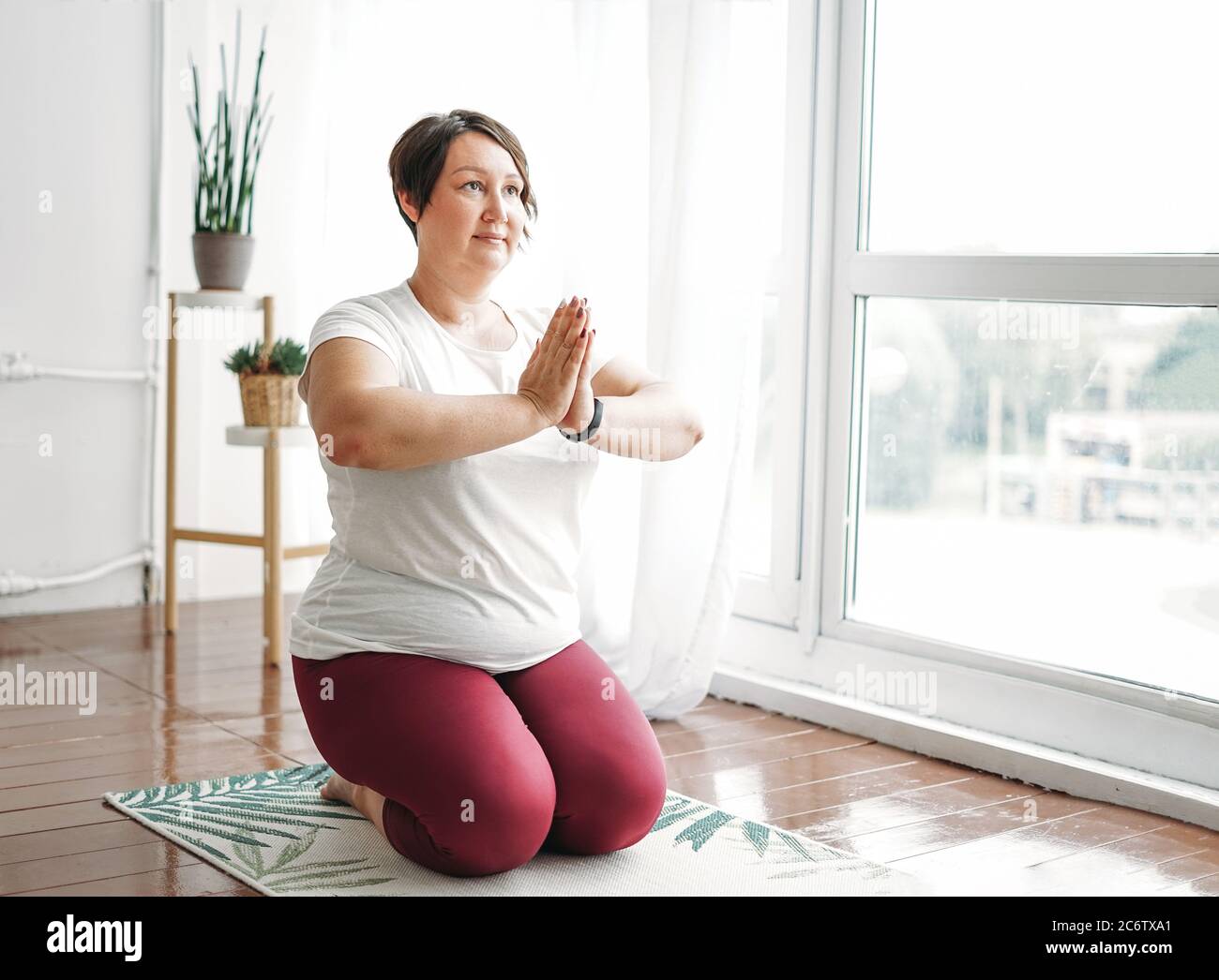 Adult charming woman plus size body positive practice yoga at