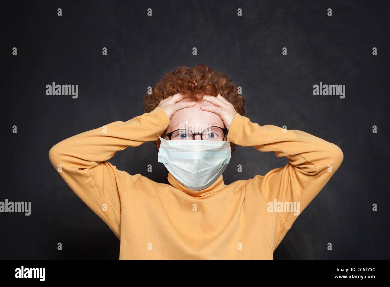 Shocked child in medical protective face mask on blackboard background ...