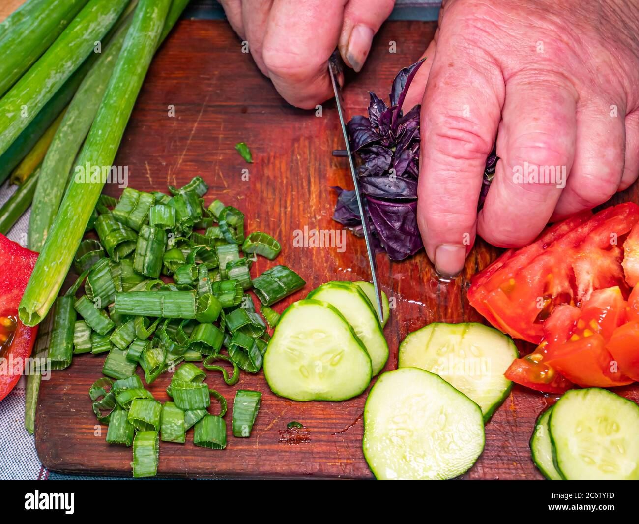 Slicing violet basil salad leaves with a knife on a cutting board. Stock Photo