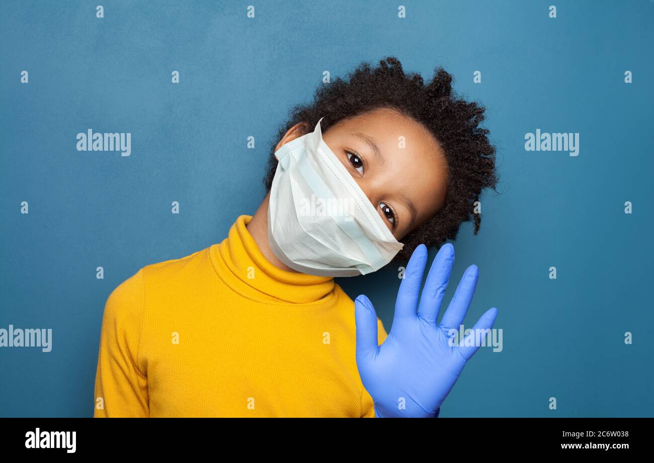 Black child boy wearing medical protective mask showing stop gesture ...