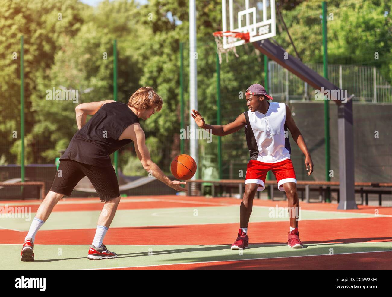 African American and Caucasian basketballers playing game match at outdoor court Stock Photo